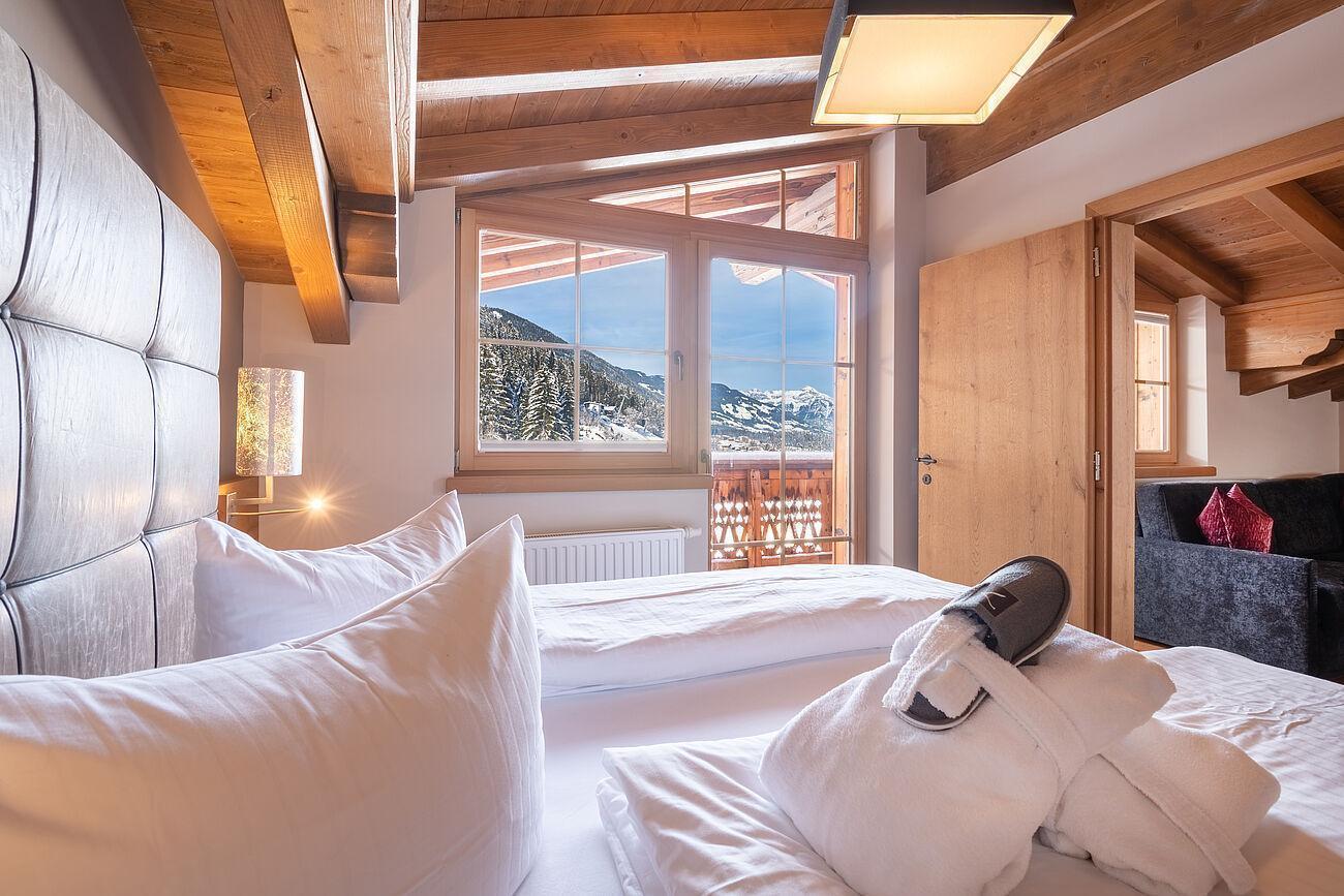 Bademäntel und -latschen auf einem Bett im Chalet