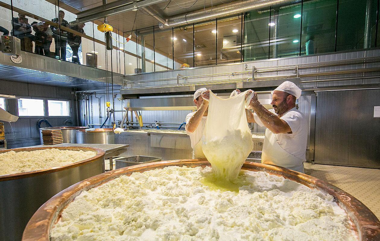 Eine Familie sieht zwei Männern bei der Herstellung von Käse zu