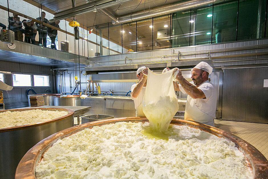Eine Familie sieht zwei Männern bei der Herstellung von Käse zu