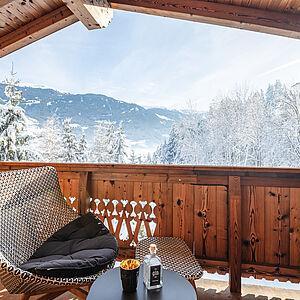 Korbstuhl steht auf einem Balkon des Naturhotels mit Blick auf die Berge