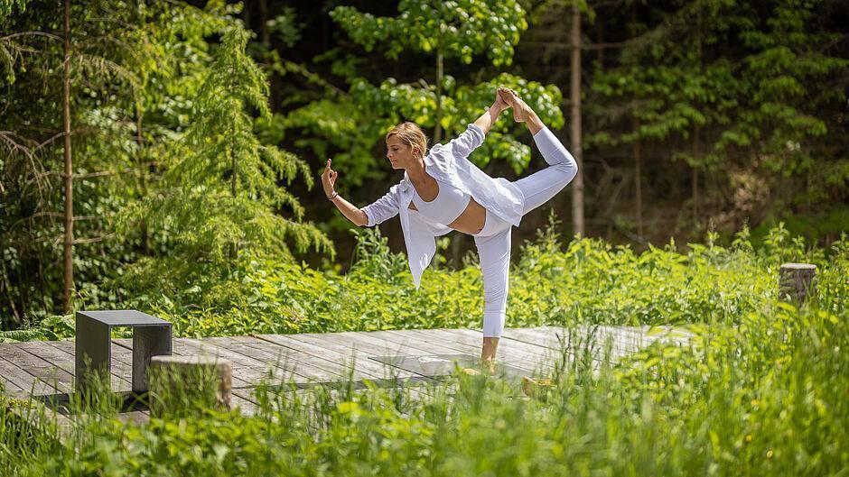 Dame in weißer Kleidung macht Yoga in der Natur im Wellnesshotel Tirol 
