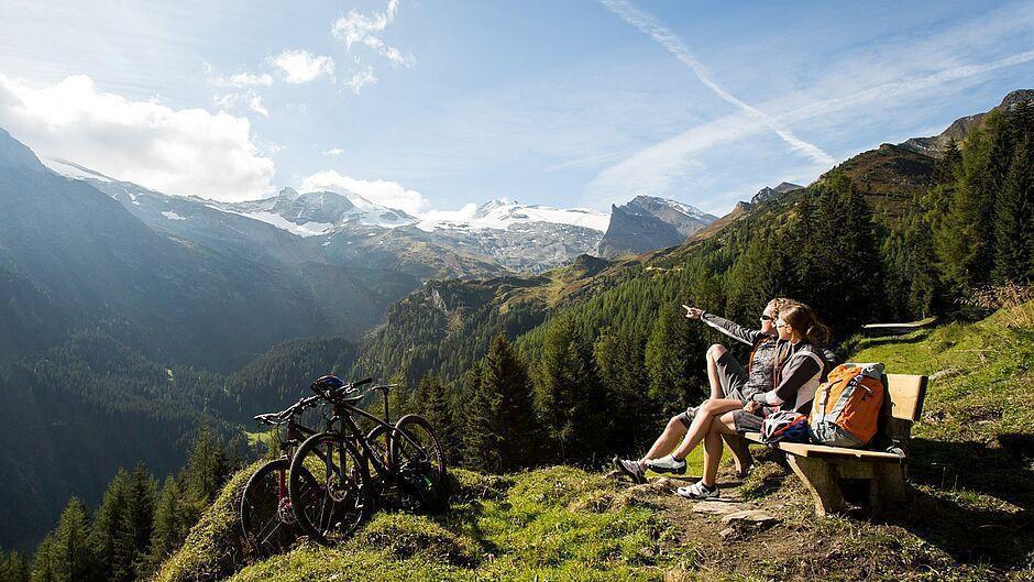 Ein Paar macht Pause auf einer Bank vom Mountainbiking in den Zillertaler Bergen