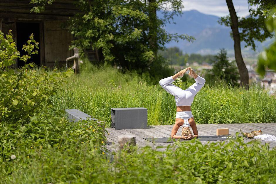 Dame macht eine Yoga Pose auf einem Steg nahe des Naturhotels Tirol 