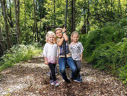 Drei kleine Kinder spielen auf einer Seilbahn im Familienurlaub in Tirol 