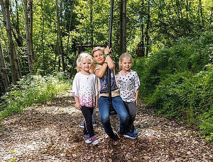 Drei kleine Kinder spielen auf einer Seilbahn im Familienurlaub in Tirol