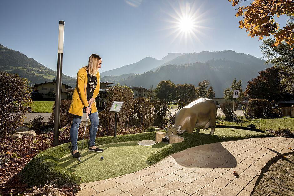 Eine Frau hat Spaß auf einer Minigolfanlage im Familienhotel in Tirol 
