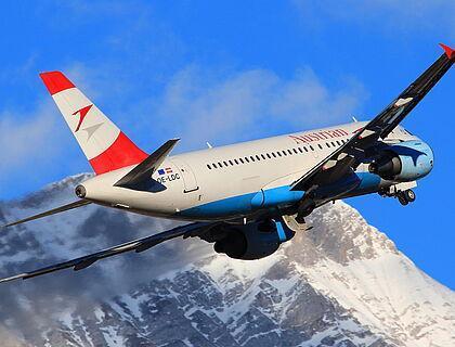 Austrian Airways Flugzeug fliegt über schneebedeckte Berge in Österreich 
