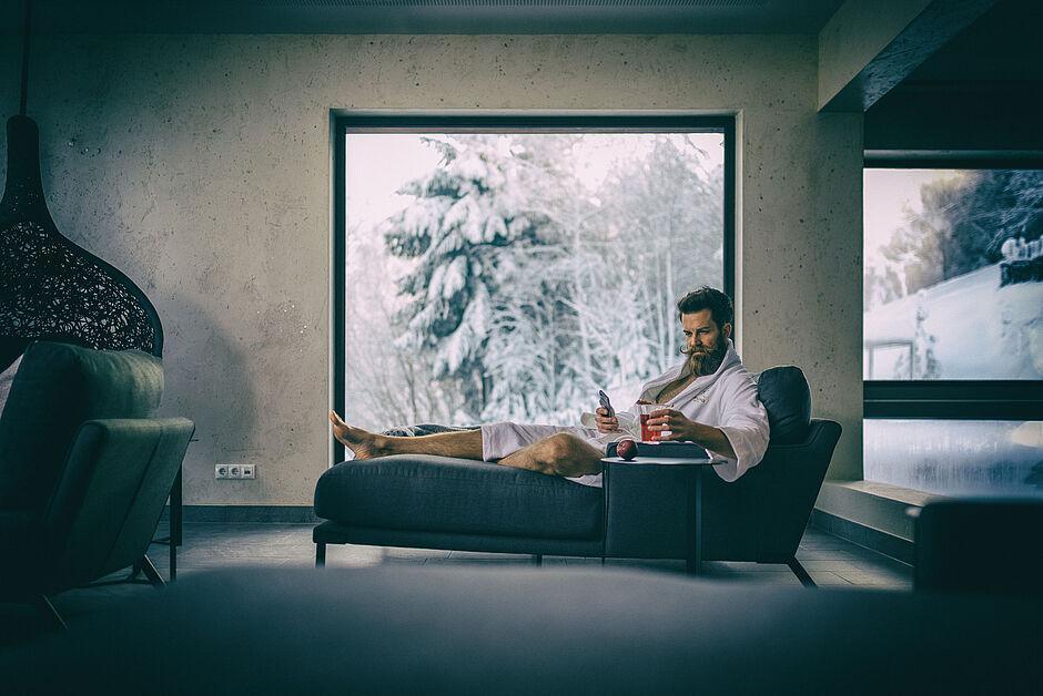 Gast genießt die Wellnesslandschaft mit einem Getränk im Hotel im Zillertal