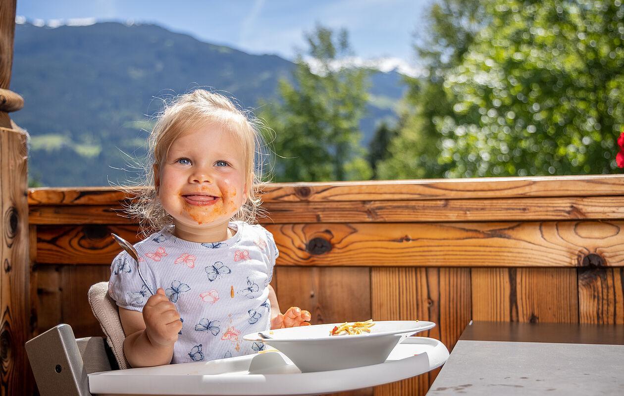 Kleinkind isst in einem Kinderstuhl Spaghetti im Familienhotel Zillertal 