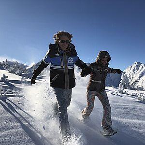 Zwei Kinder laufen fröhlich durch den Schnee in den Bergen von Österreich 