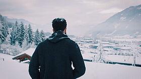 Mann blickt auf schneebedeckte Landschaft mit Hotel im Zillertal 