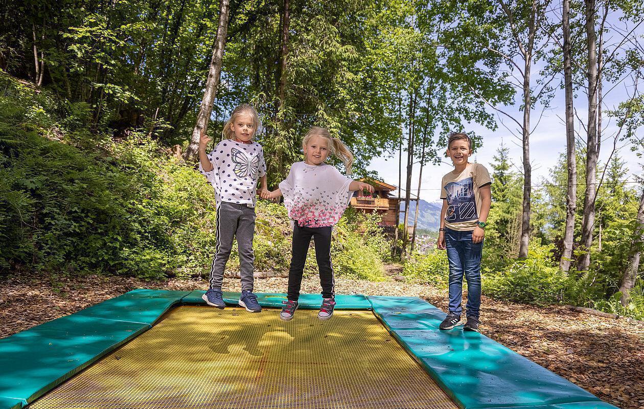 Kinder hüpfen auf einem im Boden eingelassenen Trampolin
