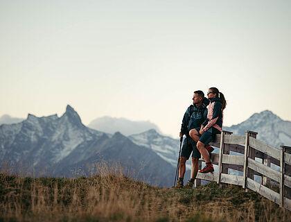 Paar lehnt an einem Weidezaun auf einer Wiese in den Bergen 