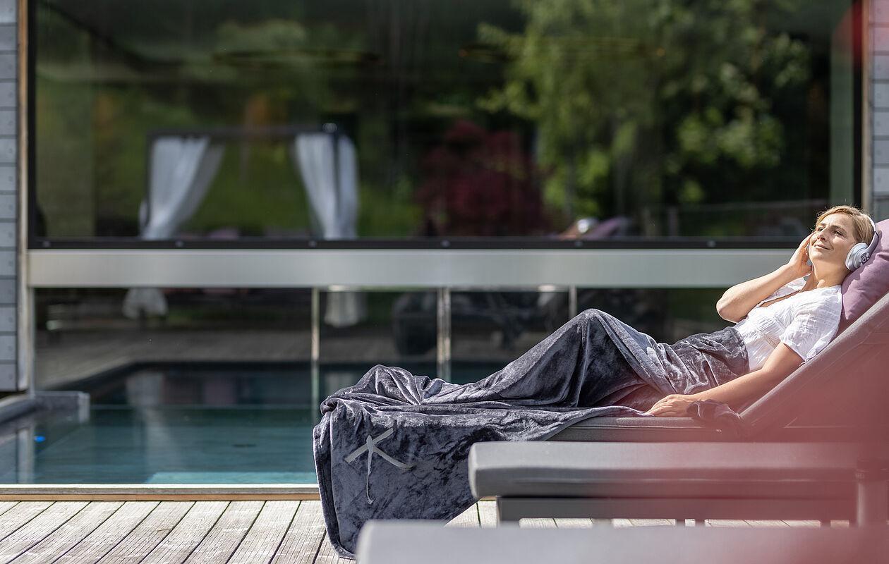 Hotelgast liegt auf einer Ruheliege im Außenbereich des Wellnesshotel Tirol