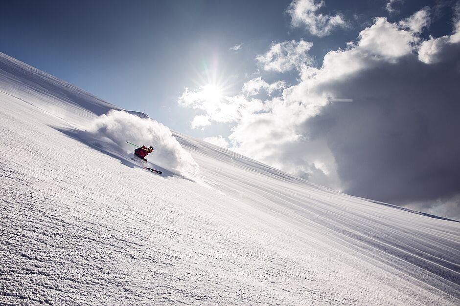 Skifahrer fährt schnell auf einer angestrahlten Skipiste im Winterurlaub 