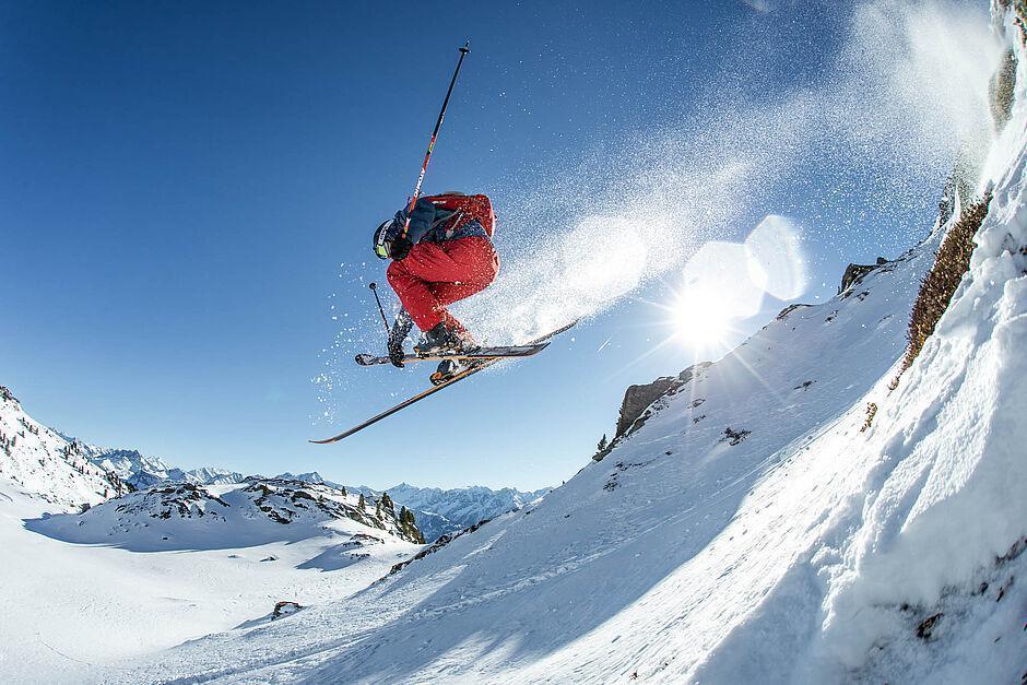 Skifahrer im Sprung vor blauem Himmel im Skigebiet Hochzillertal