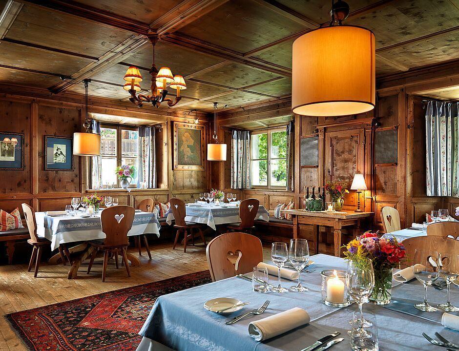 Urig eingerichtetes Restaurant mit gedeckten Tischen und leuchtenden Lampen in Tirol