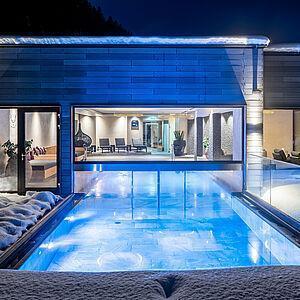 Beleuchteter Außenbereich des Wellness Hotel Tirol mit Pool bei Nacht 