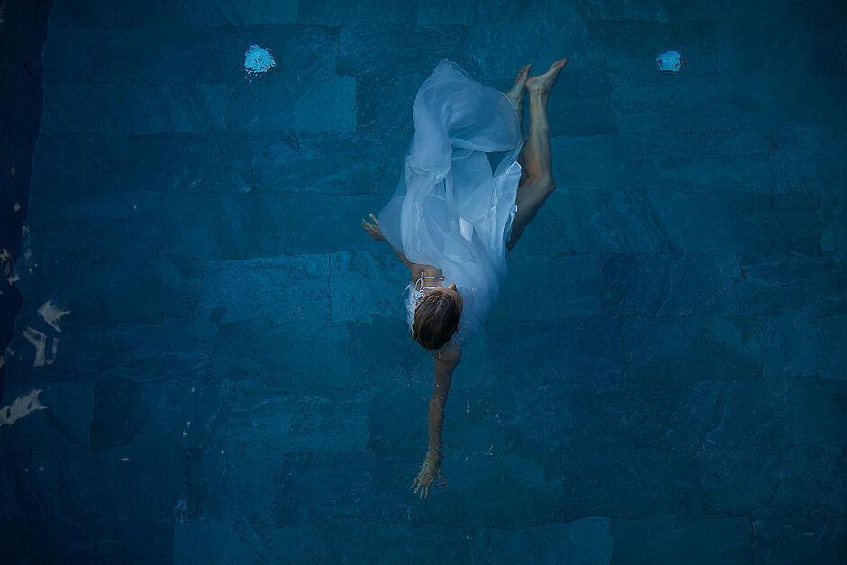 Dame schwimmt in weißem Kleid im Pool des Hotel Kaltenbach in Tirol 