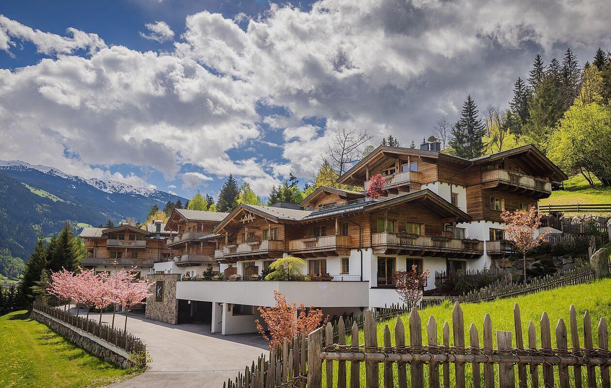 Das Hotel von außen mit blühenden Bäumen in der Sommersaison