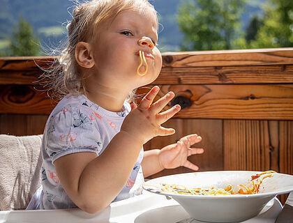 Kleines Mädchen genießt Spaghetti im Familienhotel im Zillertal 