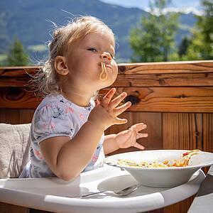 Kleines Mädchen genießt Spaghetti im Familienhotel im Zillertal 