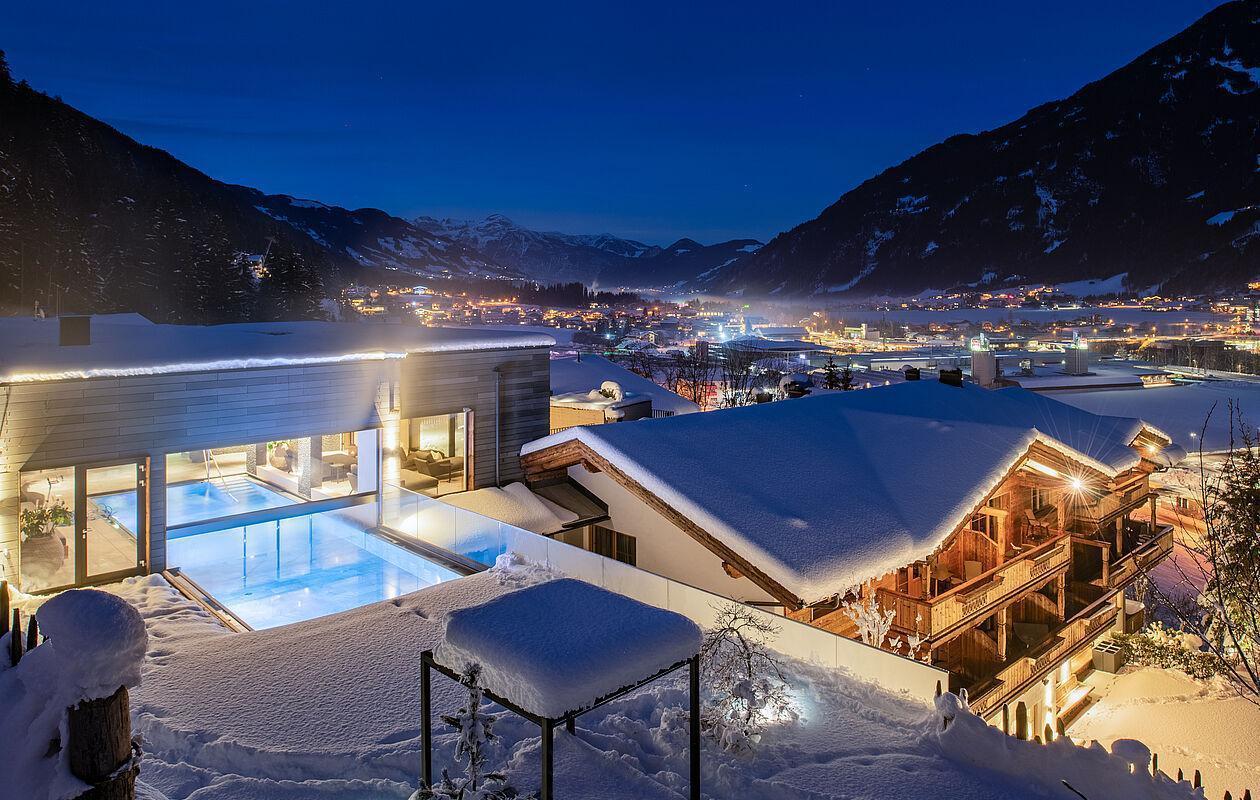 Blick auf das schneebedeckte Hotel mit Spa in Tirol am Abend