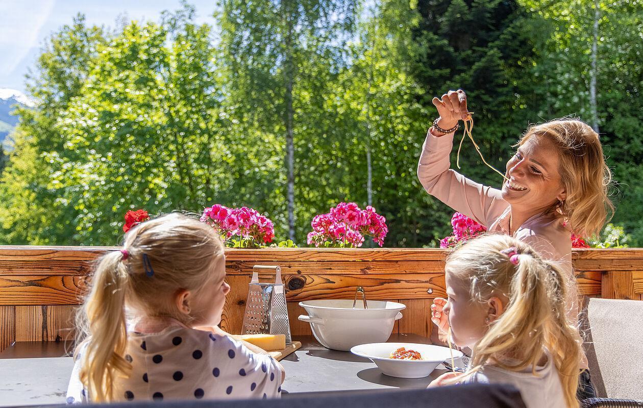 Eine Mutter und Ihre Kinder essen Pasta auf einem Balkon