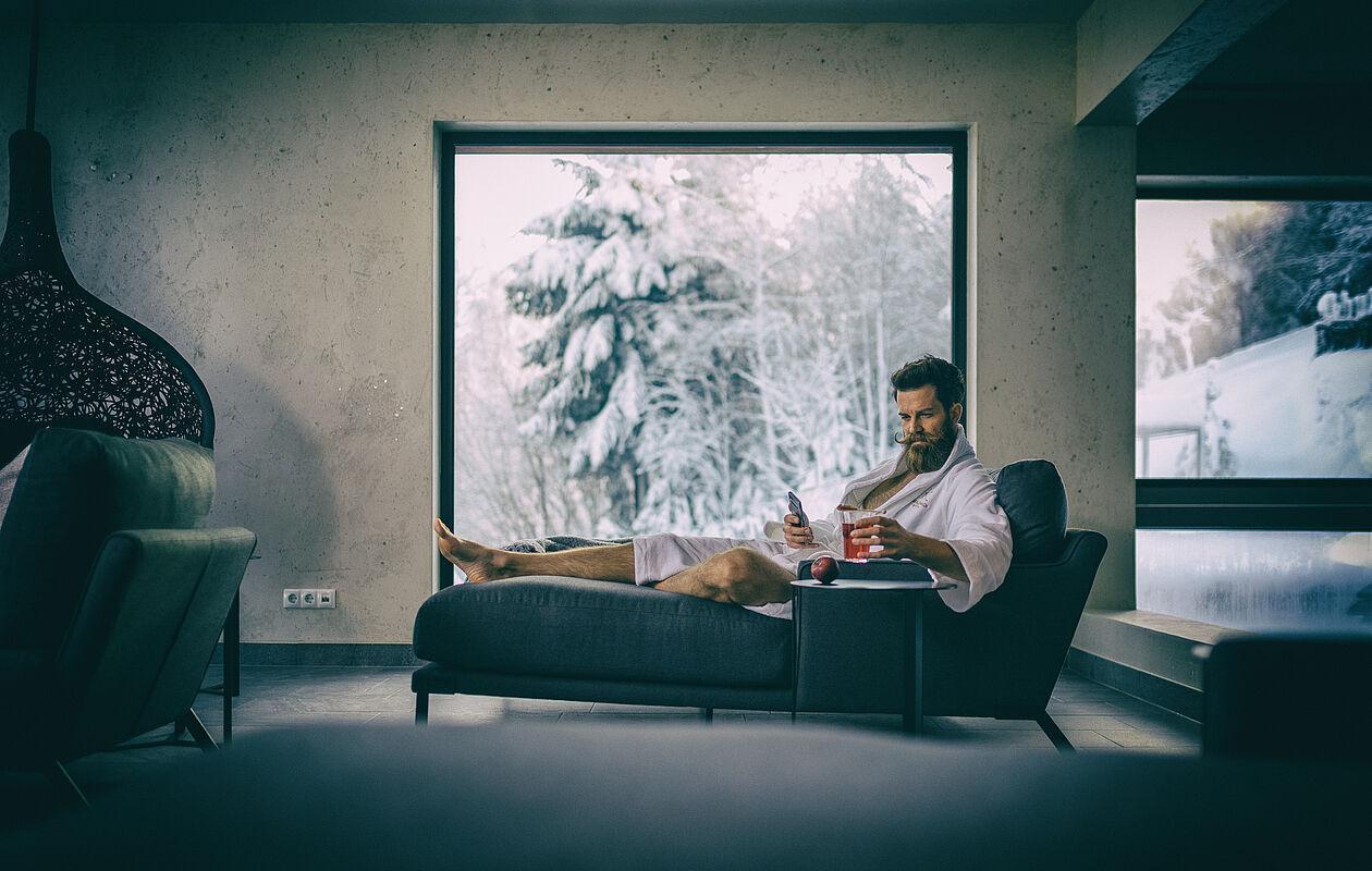 Mann im Bademantel sitzt auf einer Ruheliege im Wellnesshotel Kaltenbach