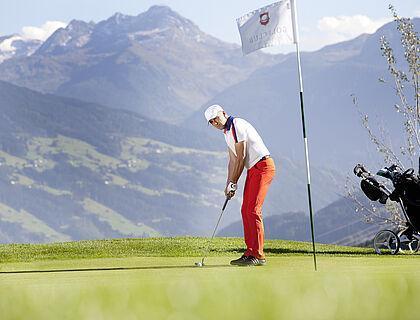 Golfer macht den letzten Putt auf dem Grün im Sommerurlaub in Tirol