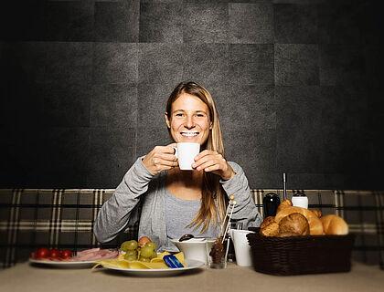 Eine Frau mit Milchbart sitzt beim Frühstück