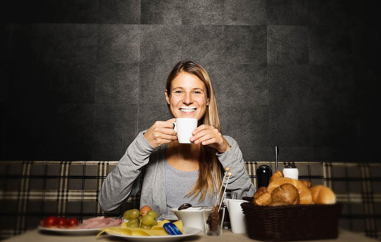 Eine Frau mit Milchbart sitzt beim Frühstück