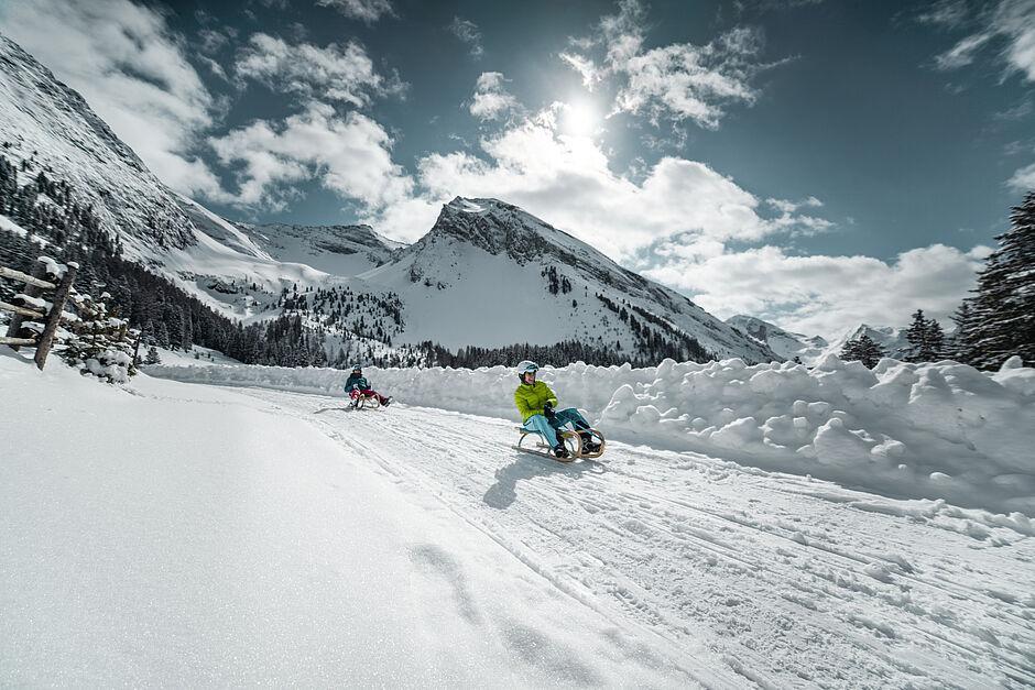Kinder fahren mit dem Schlitten auf einer Piste nahe des Familienhotel Zillertal 