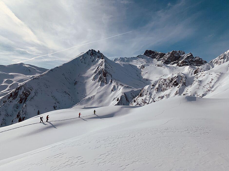 Schneebedeckte Berggipfel mit einigen Skitour-Fahrern, die den Berg hochlaufen