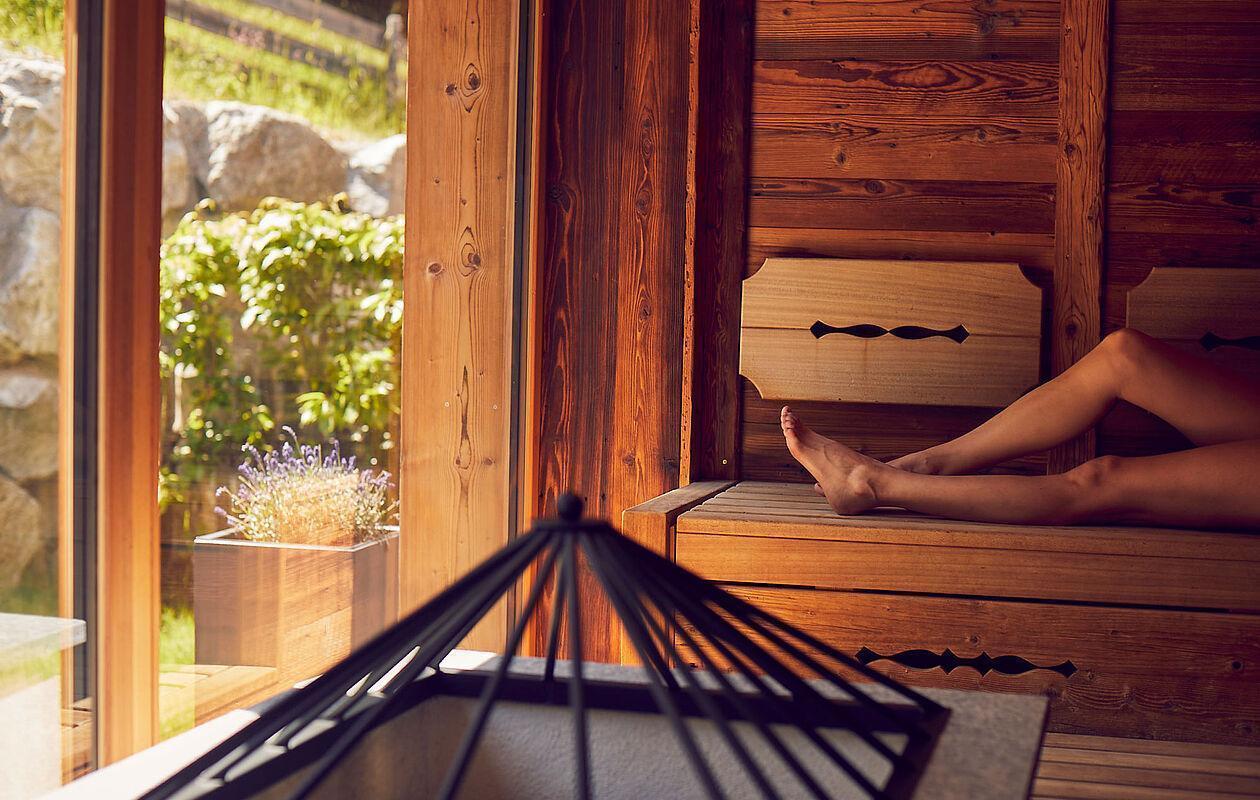 Dame entspannt in der Sauna des Wellnesshotels mit Blick ins Freie