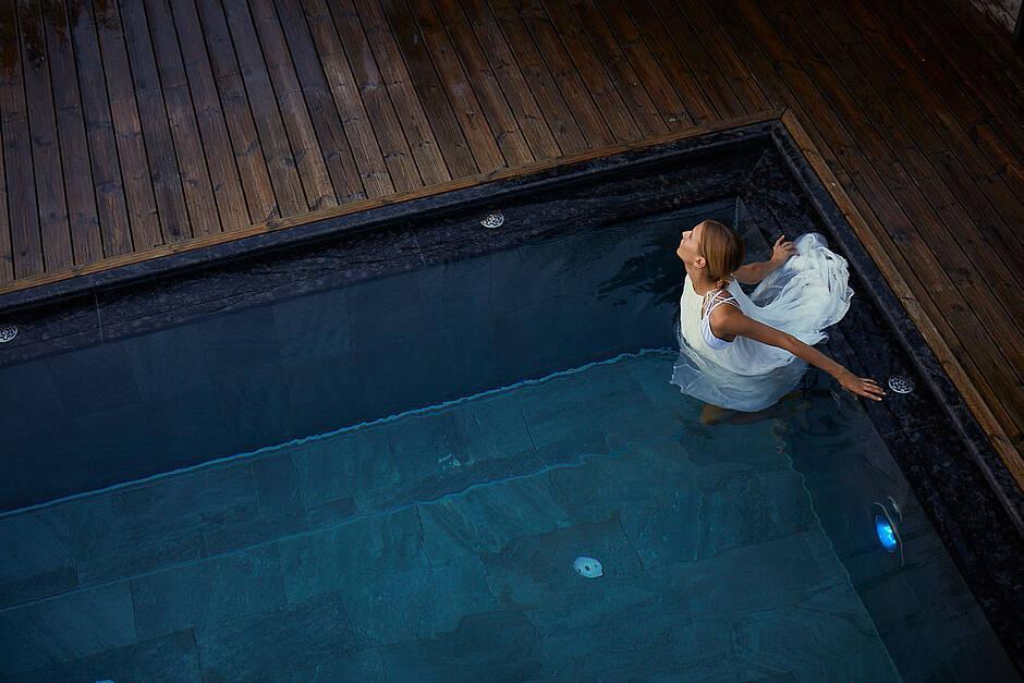 Eine Dame watet durch das klare Wasser des Infinity Pools auf dem Dach des Hotel Kaltenbach