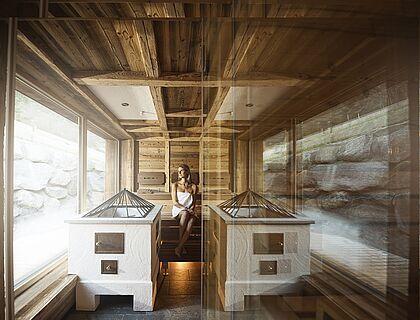 Frau sitzt in einer Panorama Sauna im Wellnesshotel Kaltenbach in Tirol