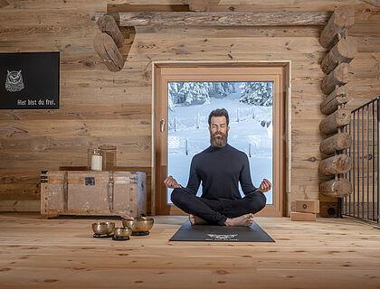 Hotelgast macht in einem mit Holz verkleidetem Raum im Wellnesshotel Tirol Yoga 