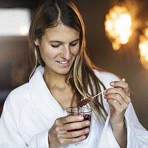 Dame im Bademantel genießt Tee mit Kristallzucker im Wellnessurlaub in Tirol