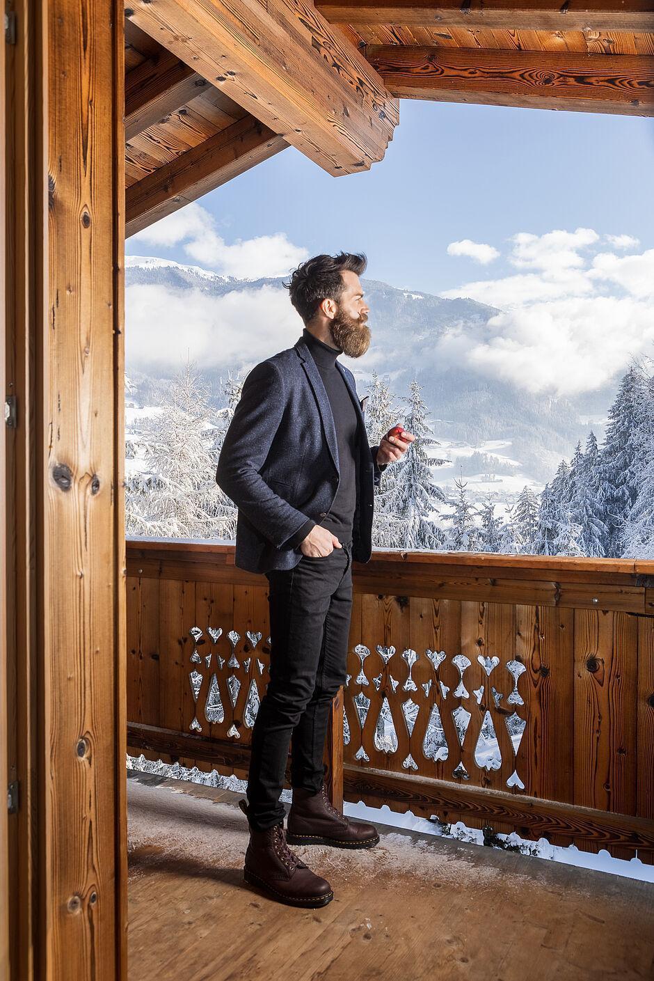 Mann steht auf einem hölzernen Balkon des Naturhotels Kaltenbach in Tirol 