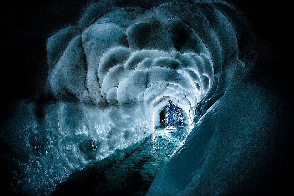 Ein Standup Paddler fährt durch das ewige Eis im Natur Eis Palast