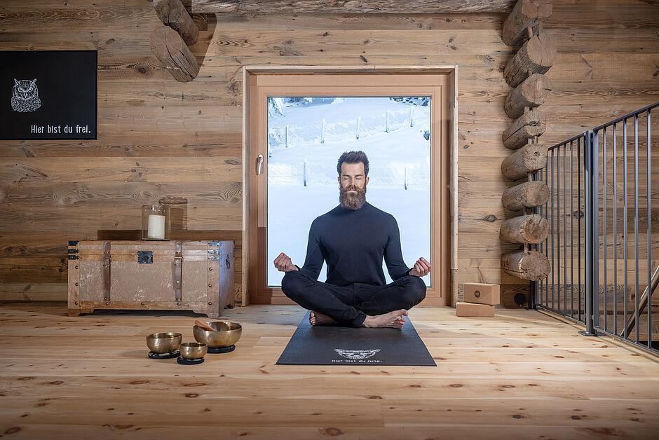 Mann sitzt in einer Yoga Position auf dem Boden des Wellnesshotels in Tirol 