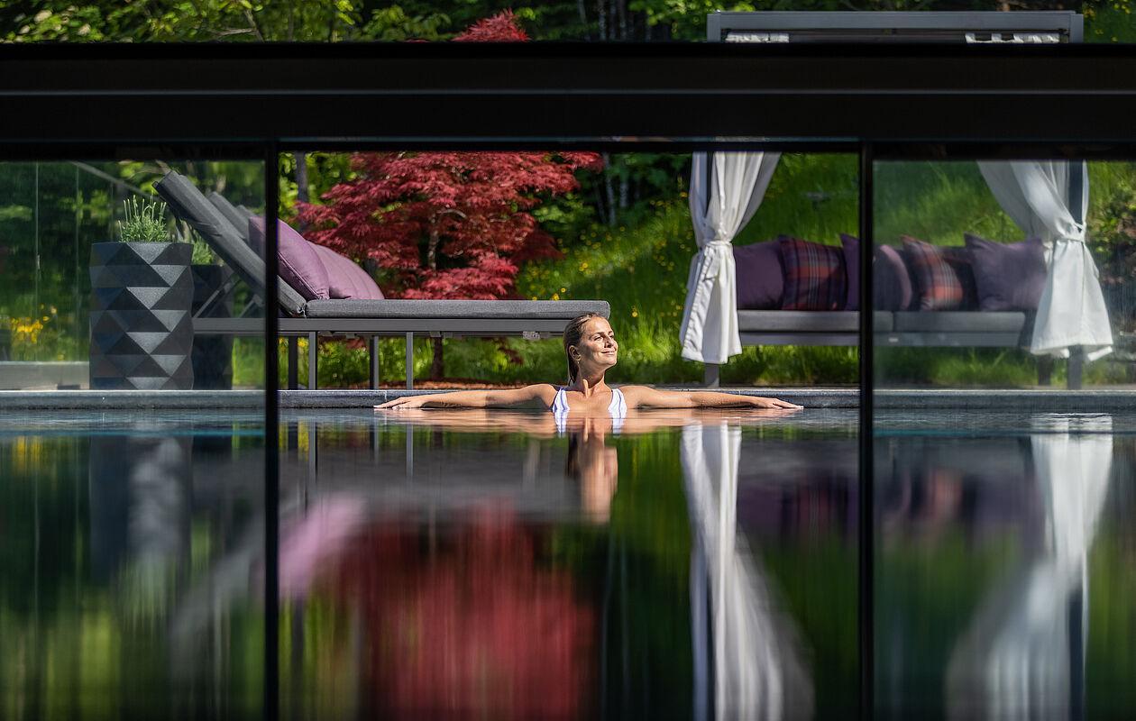 Dame genießt die Sonnenstrahlen im Pool des Wellnesshotel Tirol 
